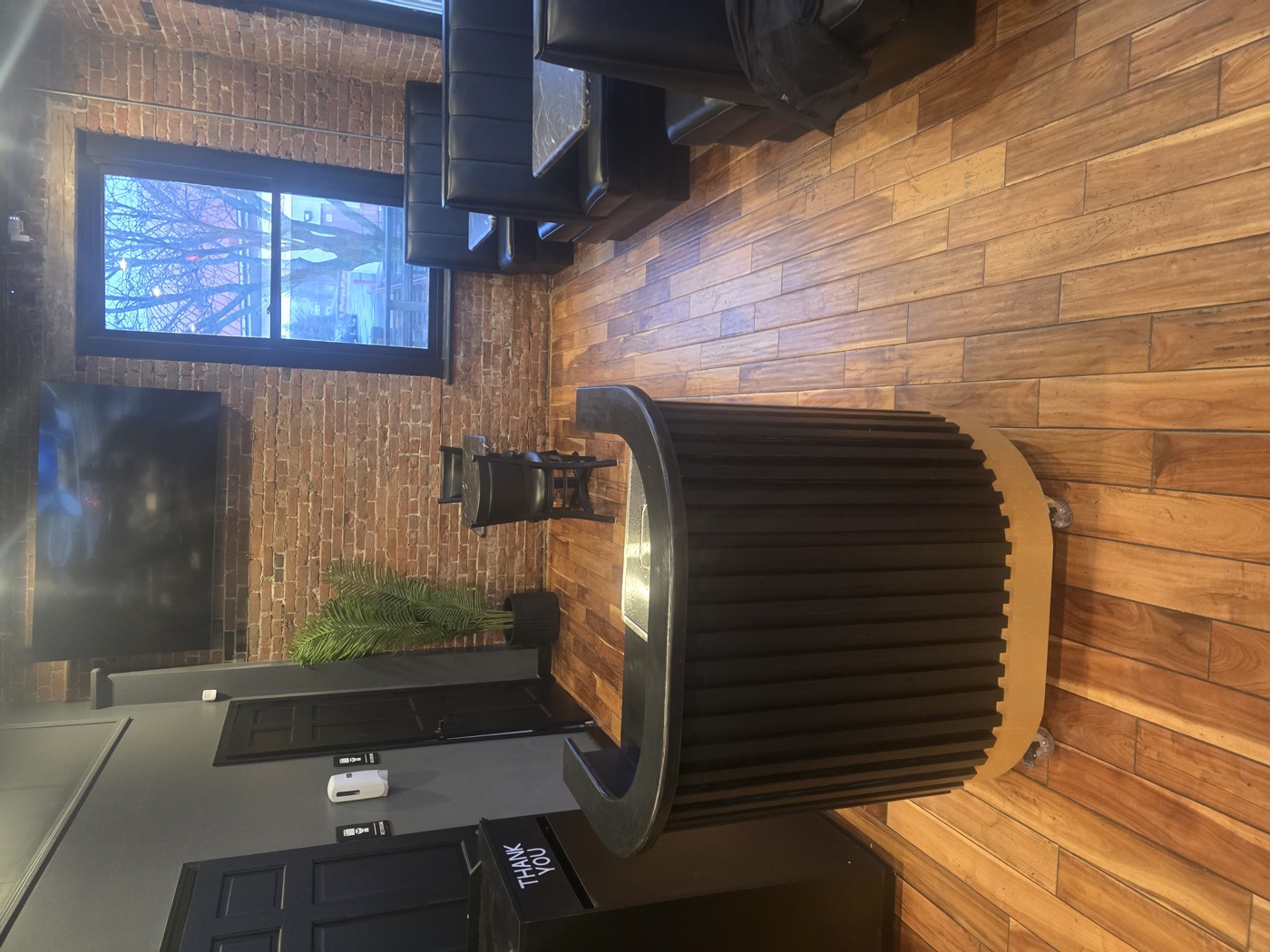 Curved black slat-front bar with a stone top in a brick-walled restaurant space