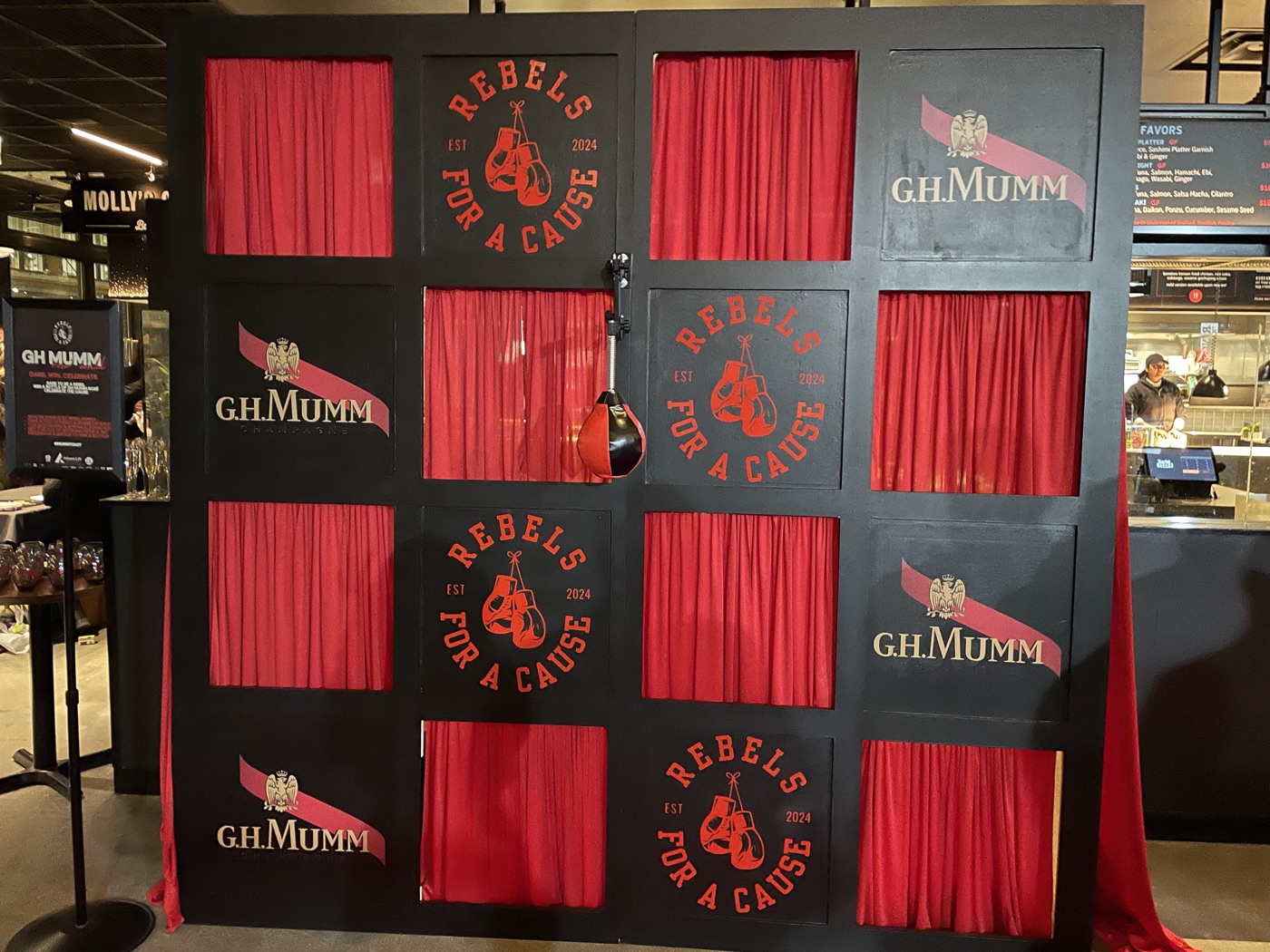 G.H. Mumm “Rebels for a Cause” branded backdrop with red drapes and hanging boxing gloves