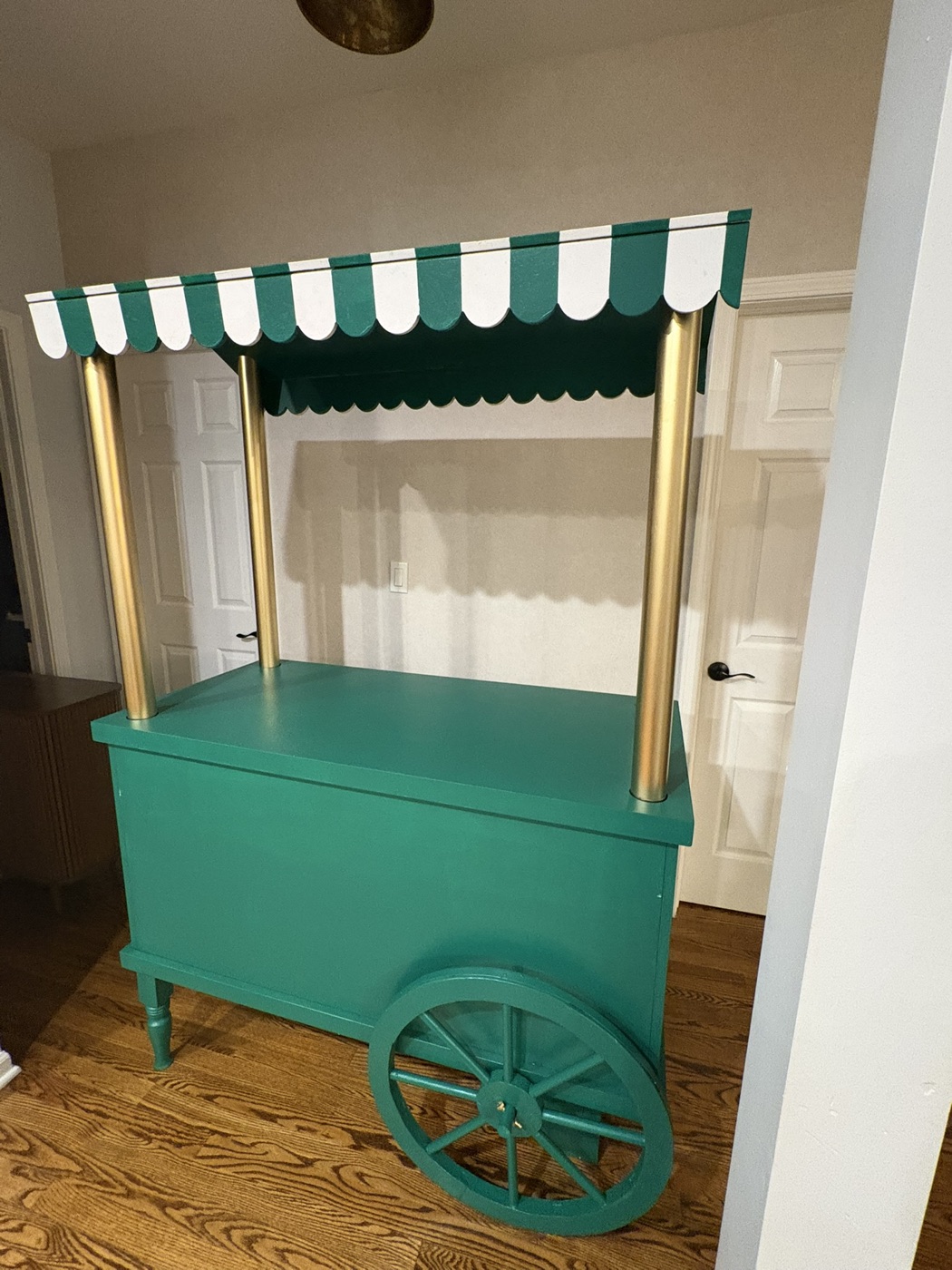 Green wheeled dessert cart with a scalloped striped canopy and gold posts